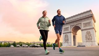 Male and female runners wearing Asics Gel-Nimbus 26 run past Arc de Triomphe