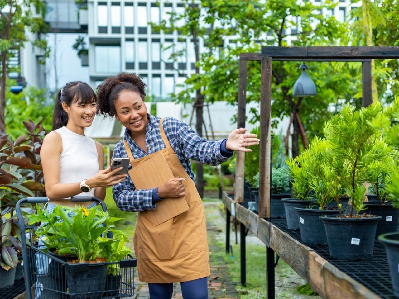 A nursery employee helping a woman shop for small trees