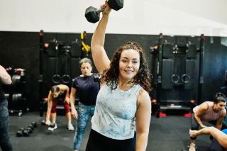 Woman in a group exercise class performing the dumbbell snatch
