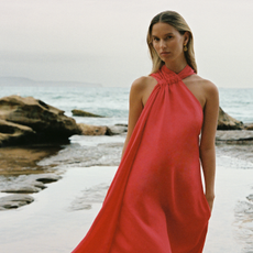 Model wearing a red Reiss dress on the beach