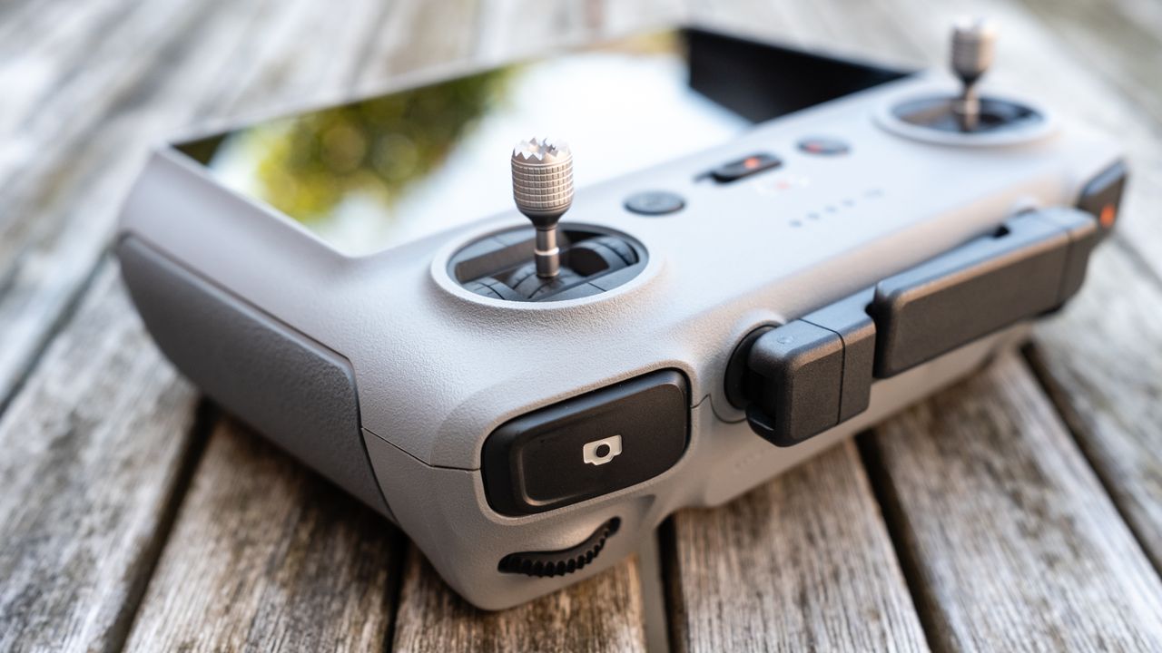 an angular view of a drone controller with edge buttons, joysticks and a screen, and folded antenna.