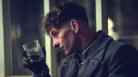 Barry Keoghan tips a whiskey glass towards a window