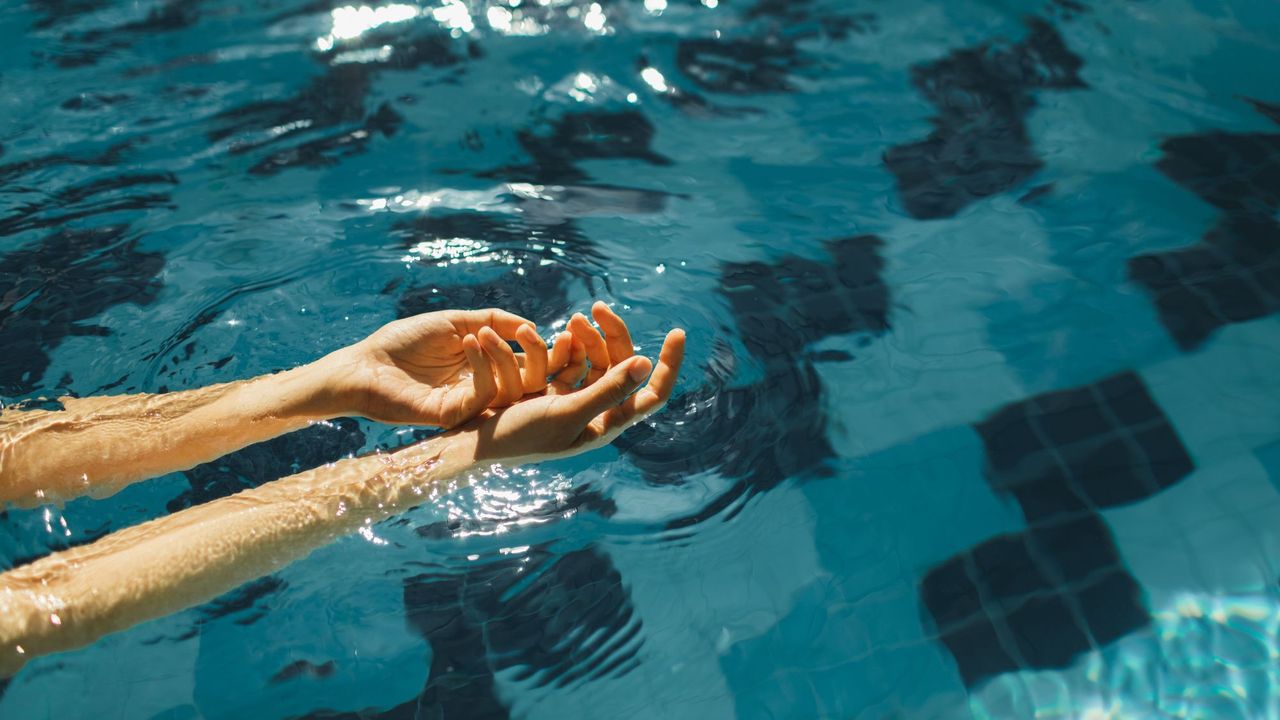 woman&#039;s hands in swimming pool