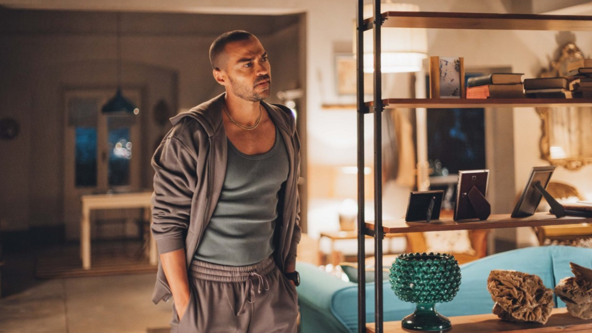 Daniel De Luca (Jesse Williams) in sweatpants and a hoodie stands in a hotel room in a scene from Prime Video's "Hotel Costiera"