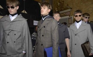Group of models stood in a line with grey jackets on