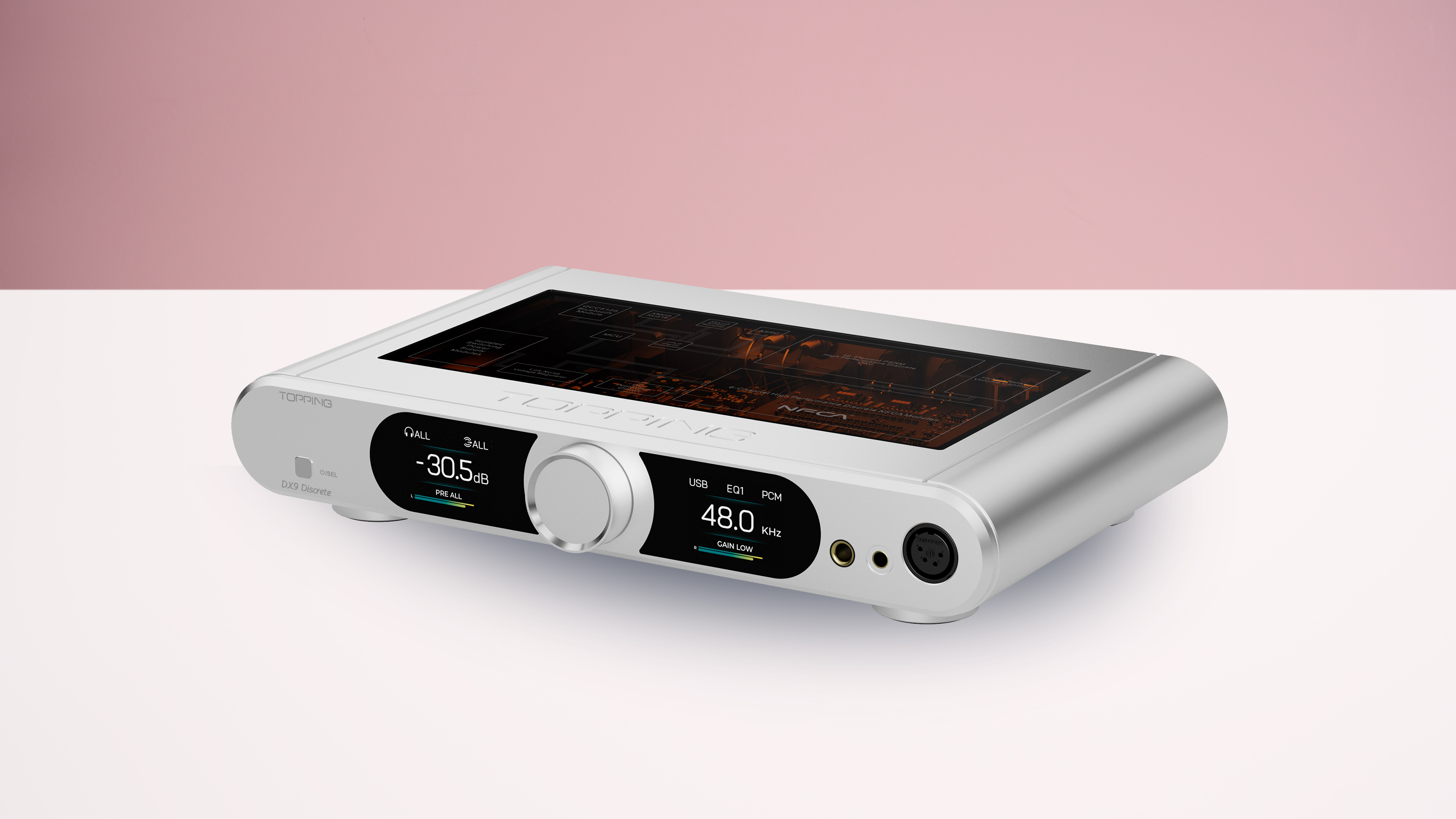 The Topping DX9 Discrete in a silver finish, on a white surface with a pink background