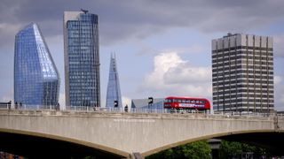 a Go-Ahead bus driving over Waterloo Bridge with skyscrapers in the background