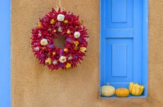 red chile wreath on building with gourds on a blue ledge