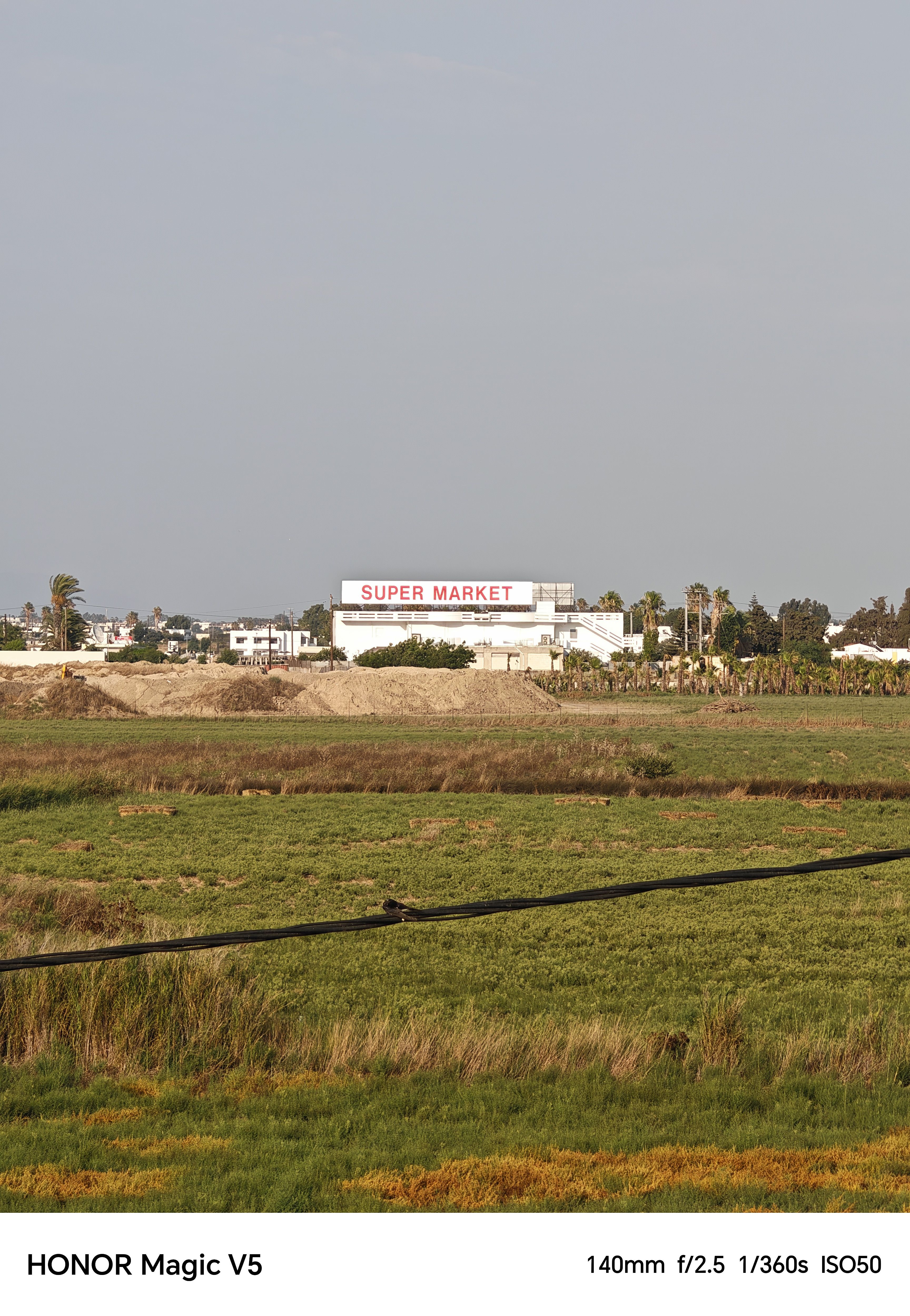 Green fields with a supermarket in the background