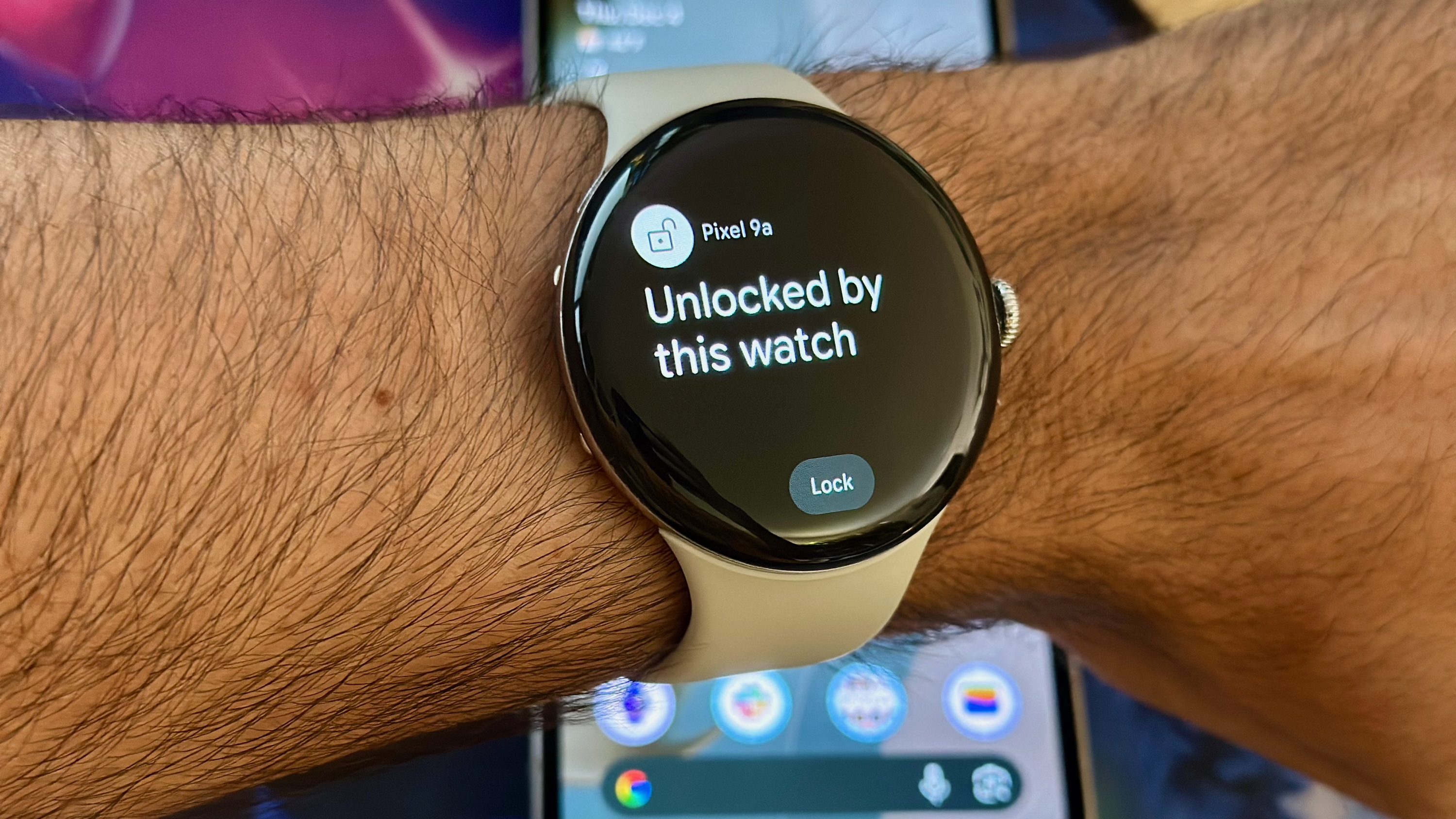A photo of the Google Pixel Watch 4 worn above a Pixel 9a, showing the pop-up 