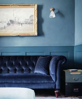 Blue living room with blue velvet sofa and small glass wall lights