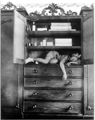 black and white photo of a woman lying within a cupboard