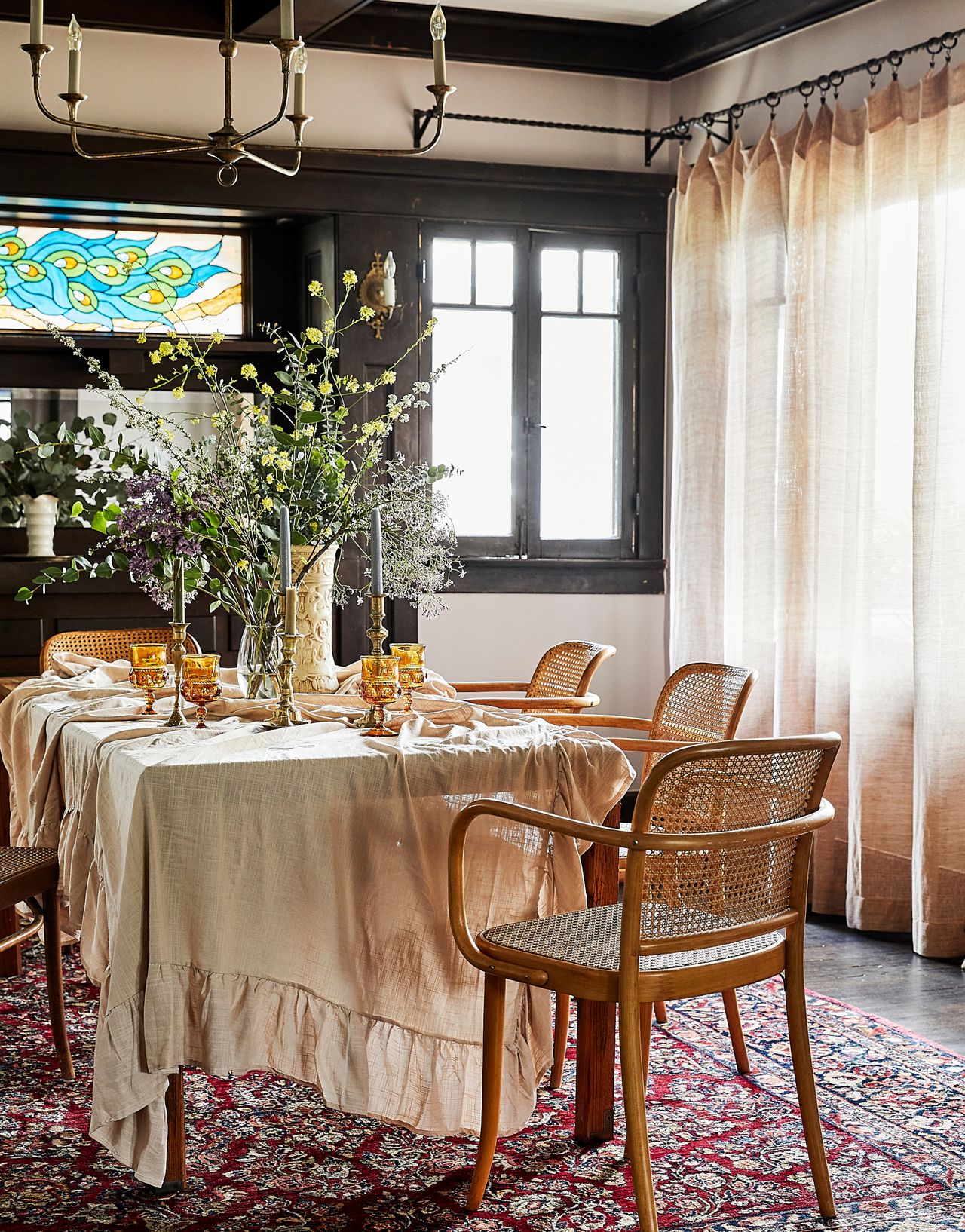 dining room with stained glass window, cane chairs and red patterned rug