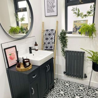 @renovation_at_5a's black boho bathroom with a small sink, a ladder with a towel that has a geometric pattern and plants
