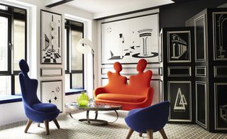 Hotel room with black and white picture walls and orange and blue furniture