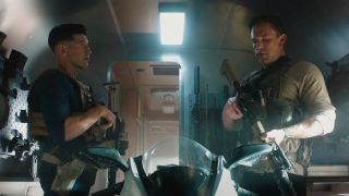 Brax and Christian standing in a trailer with guns strapped to them in The Accountant 2