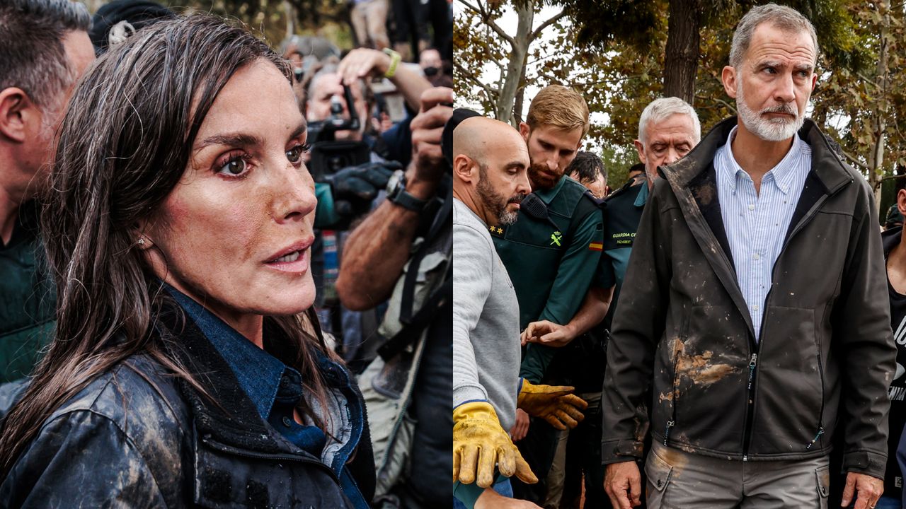 Queen Letizia and King Felipe of Spain wearing mud-stained jackets in a crowd of people