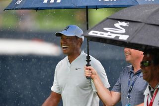 Tiger Woods smiles under an umbrella