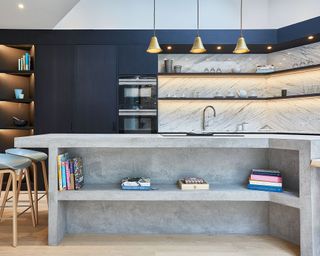 Modern kitchen with concrete island and blue cabinets with LED lighting