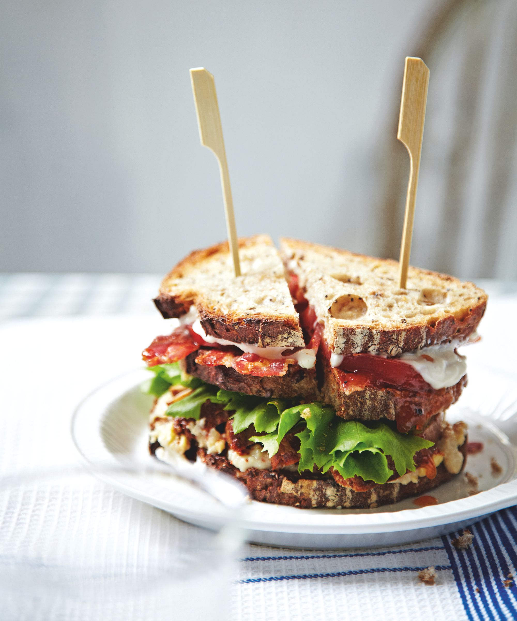 Club sandwich on a white plate with and a blue and white napkin