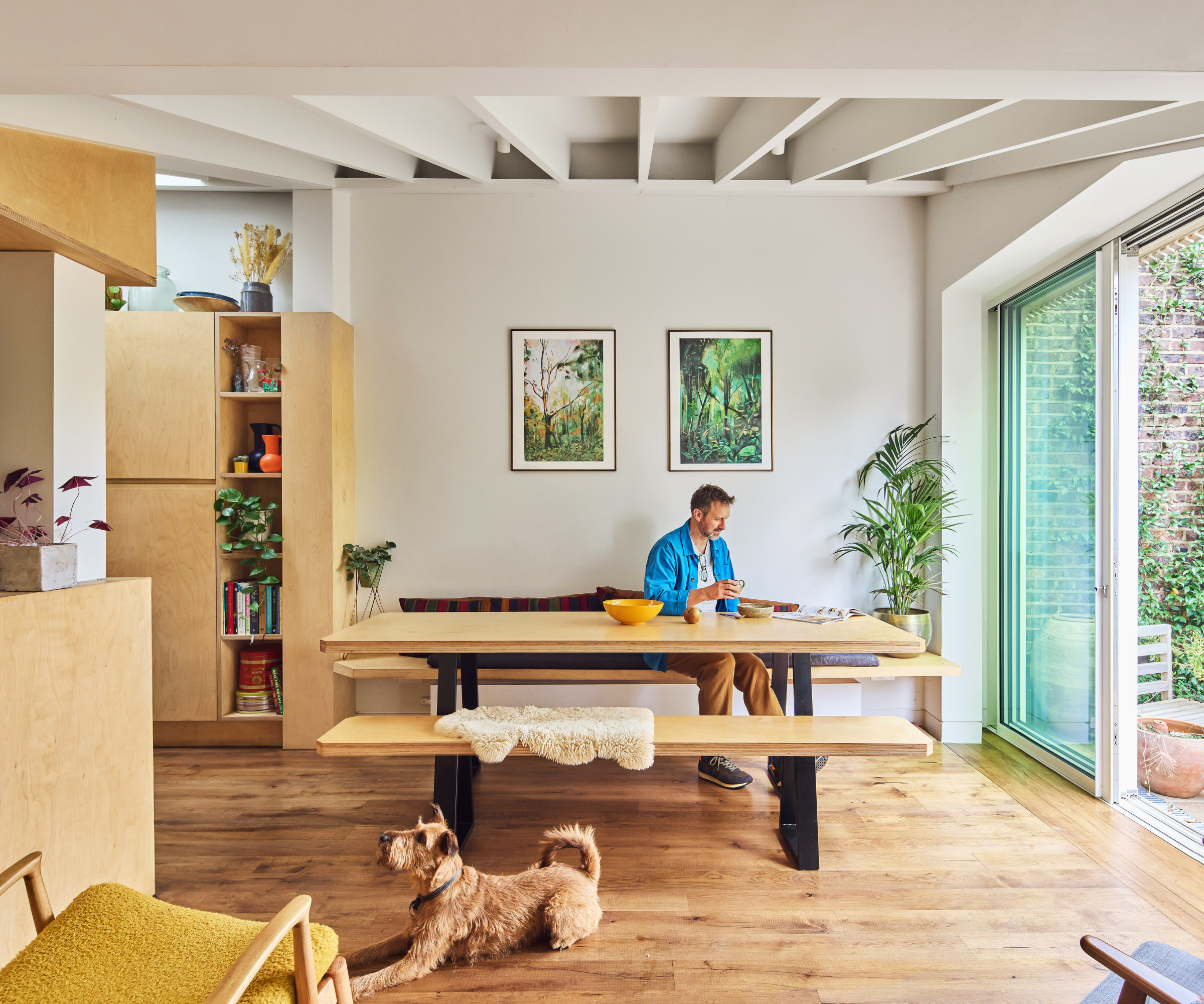 Man sitting at a table in a dining area which has patio doors opening up onto the garden