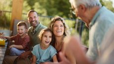 A family smiles and laughs as they listen to Grandpa tell a story.