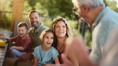 A family smiles and laughs as they listen to Grandpa tell a story.