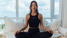 woman sits with legs crossed doing breathing exercises 