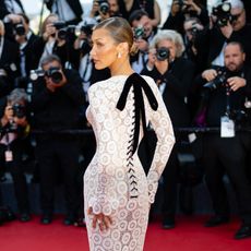 Bella Hadid looks over her shoulder wearing a white lace dress in Cannes
