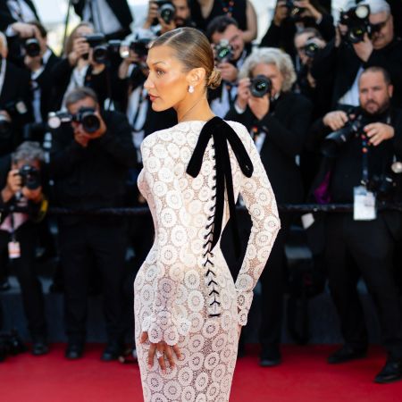 Bella Hadid looks over her shoulder wearing a white lace dress in Cannes