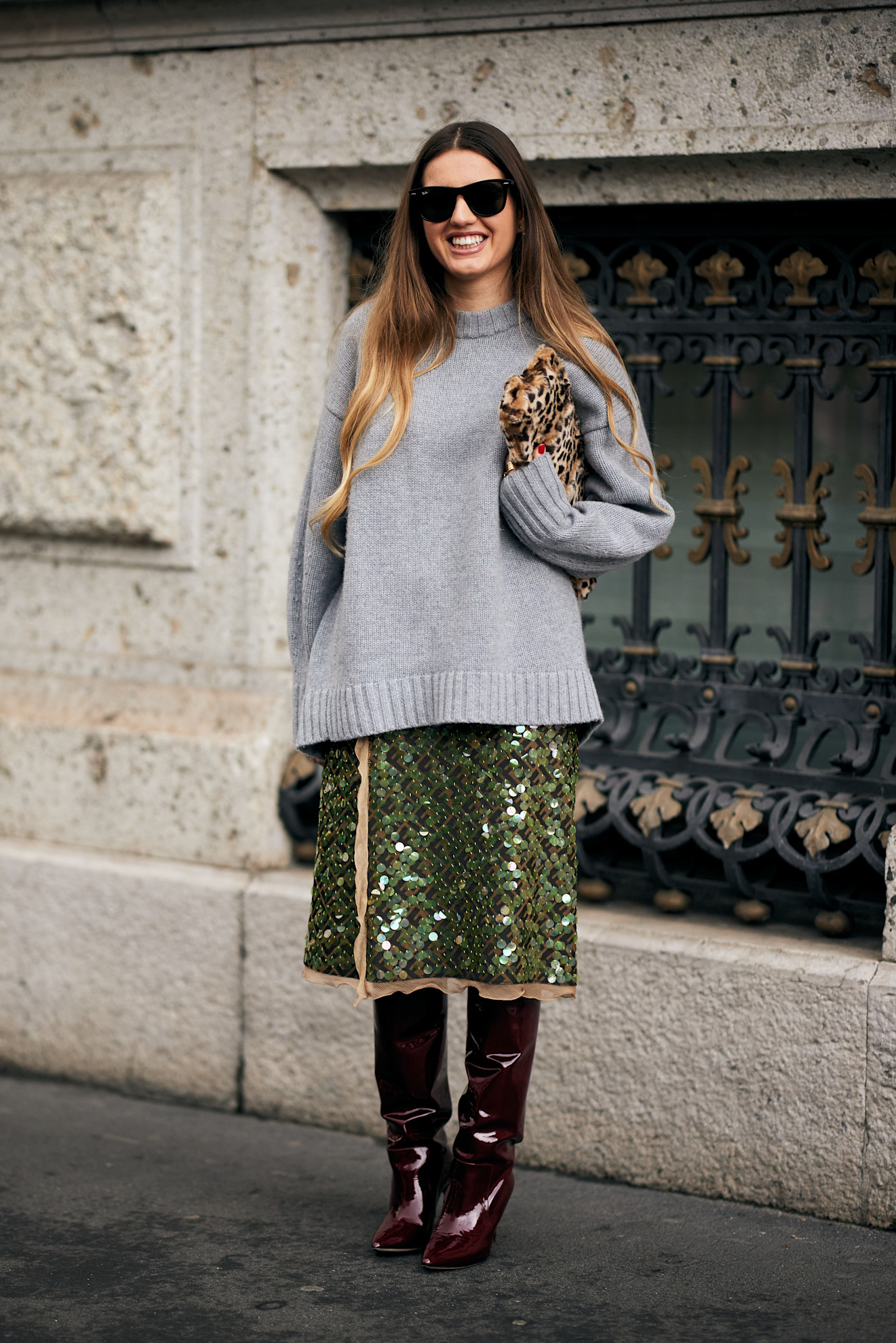 a woman wearing a grey cashmere jumper, sequin skirt and knee-high boots during milan fashion week