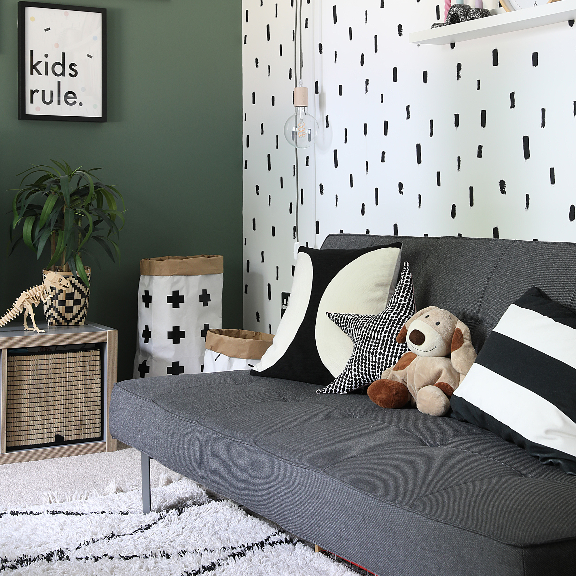 play room with grey sofa one green wall and white wall with black specs and poster on the wall saying kids rule