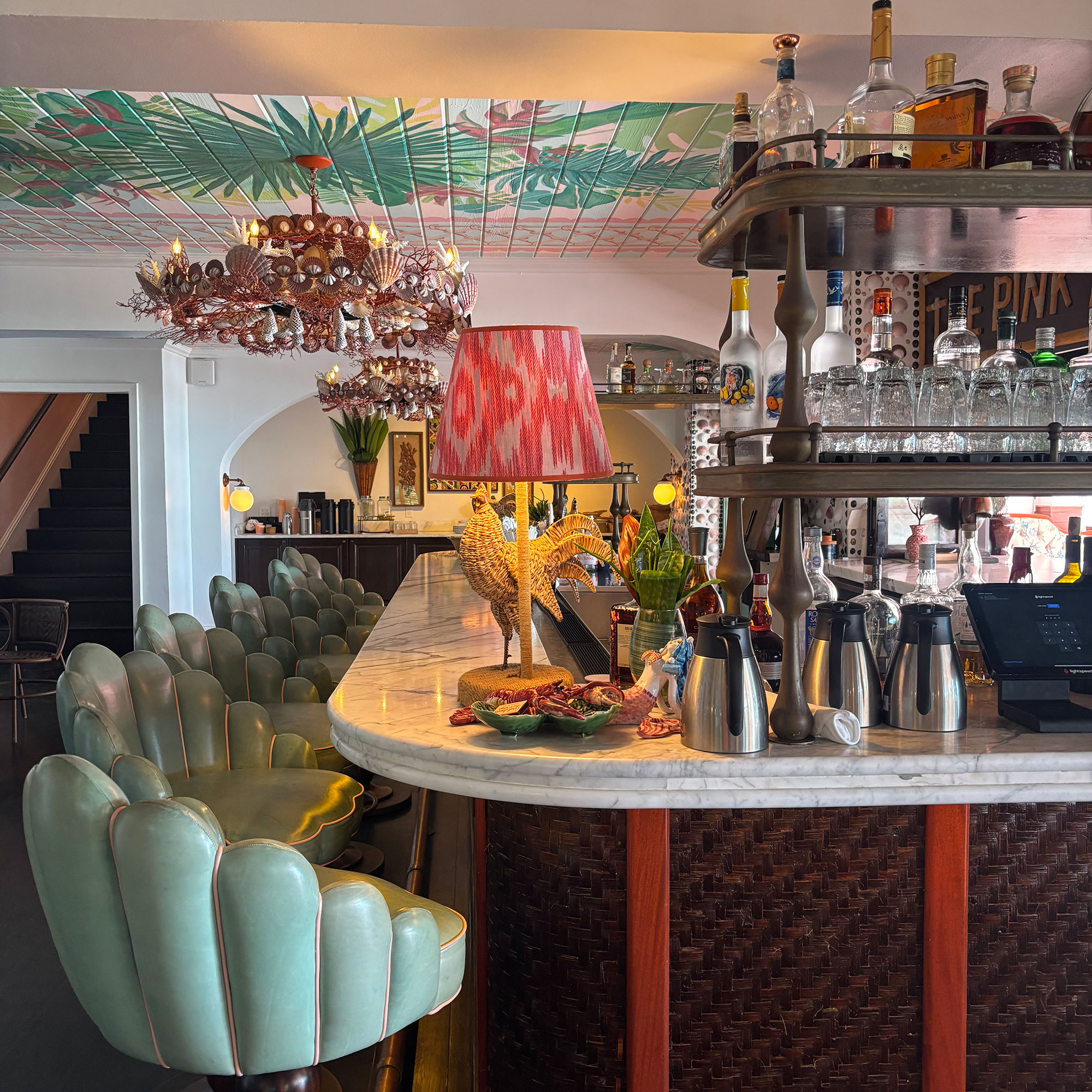 Marble topped bar with rounded corners surrounded by scalloped mint green bar stools