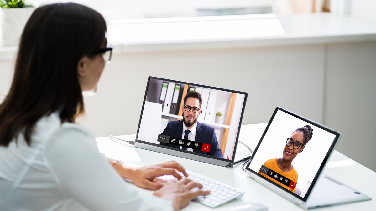 Woman sat at desk video conferencing on two screens