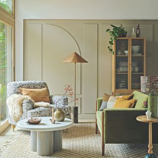 Living room with beige panelled walls, a green sofa, a floral printed snuggle and a natural rug