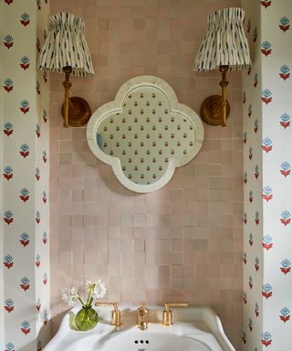 pink tiled bathroom with wallpaper and fabric lampshades on wall sconces