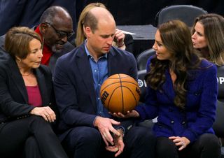 Massachusetts Governor-elect Maura Healey (L) watches as Britain's Prince William is handed a basketball by Catherine, Princess of Wales during the National Basketball Association game between the Boston Celtics and the Miami Heat at TD Garden in downtown Boston,on November 30, 2022