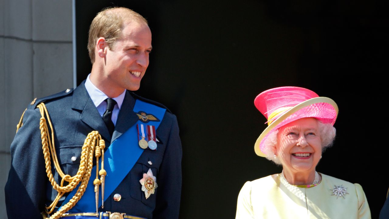 Prince William wears military uniform and smiles at Queen Elizabeth on the Buckingham Palace balcony, she wears a bright pink hat