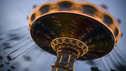 Theme park ride called a spinning carousel in a blur of motion at dusk.
