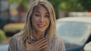 Emilia Harcourt 2 smiling with relief and holding her hands to her chest in Peacemaker season 2 episode 3