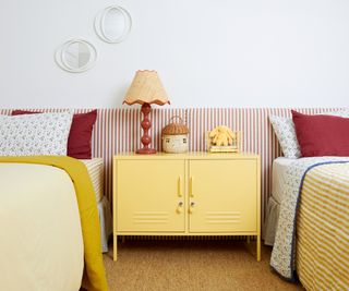 long striped headboard behind two single beds and yellow locker in middle