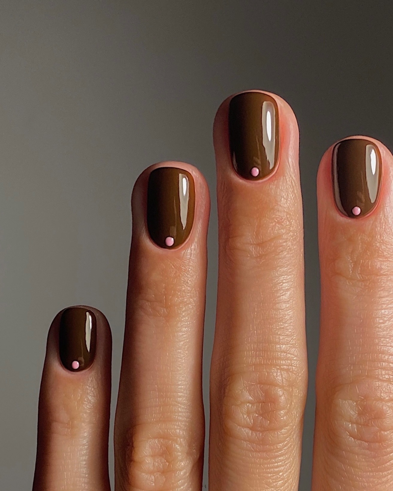 Glossy chocolate brown nails with a pale pink dot