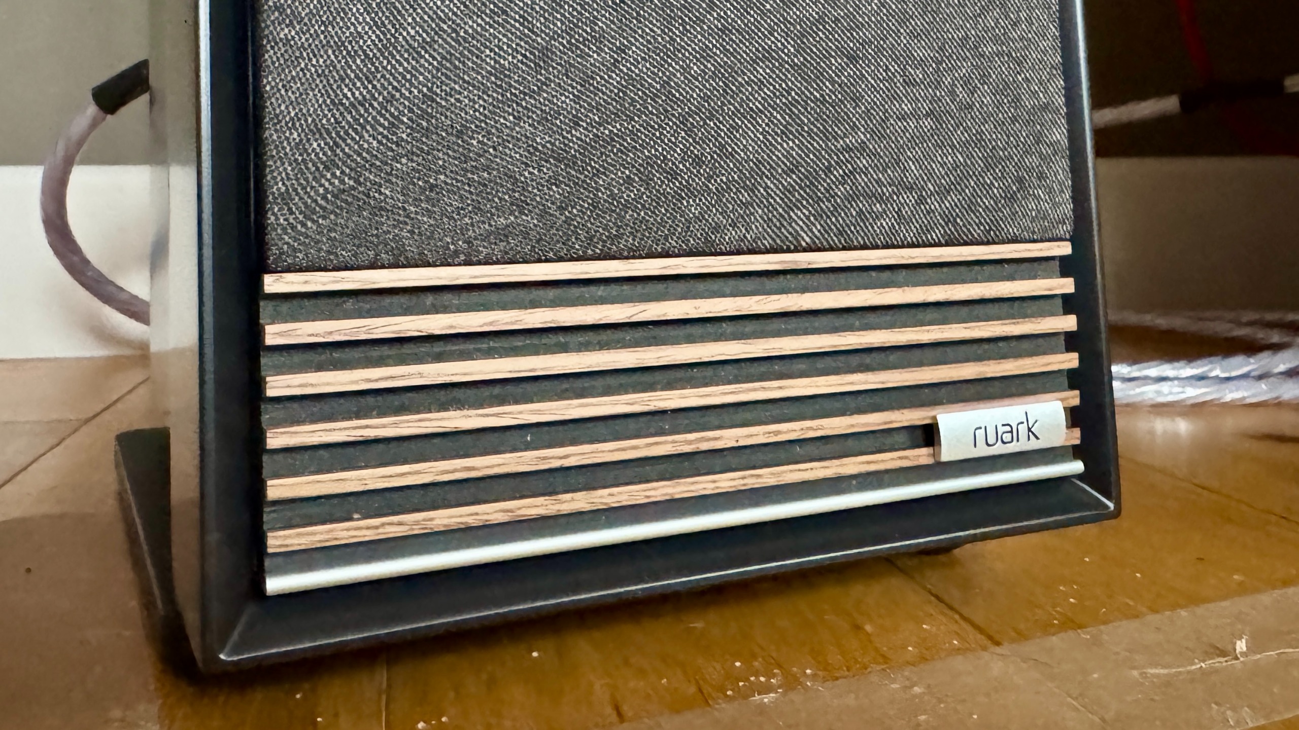 Close-up of the Ruark Audio Talisman-R speaker grille, on a wooden floor