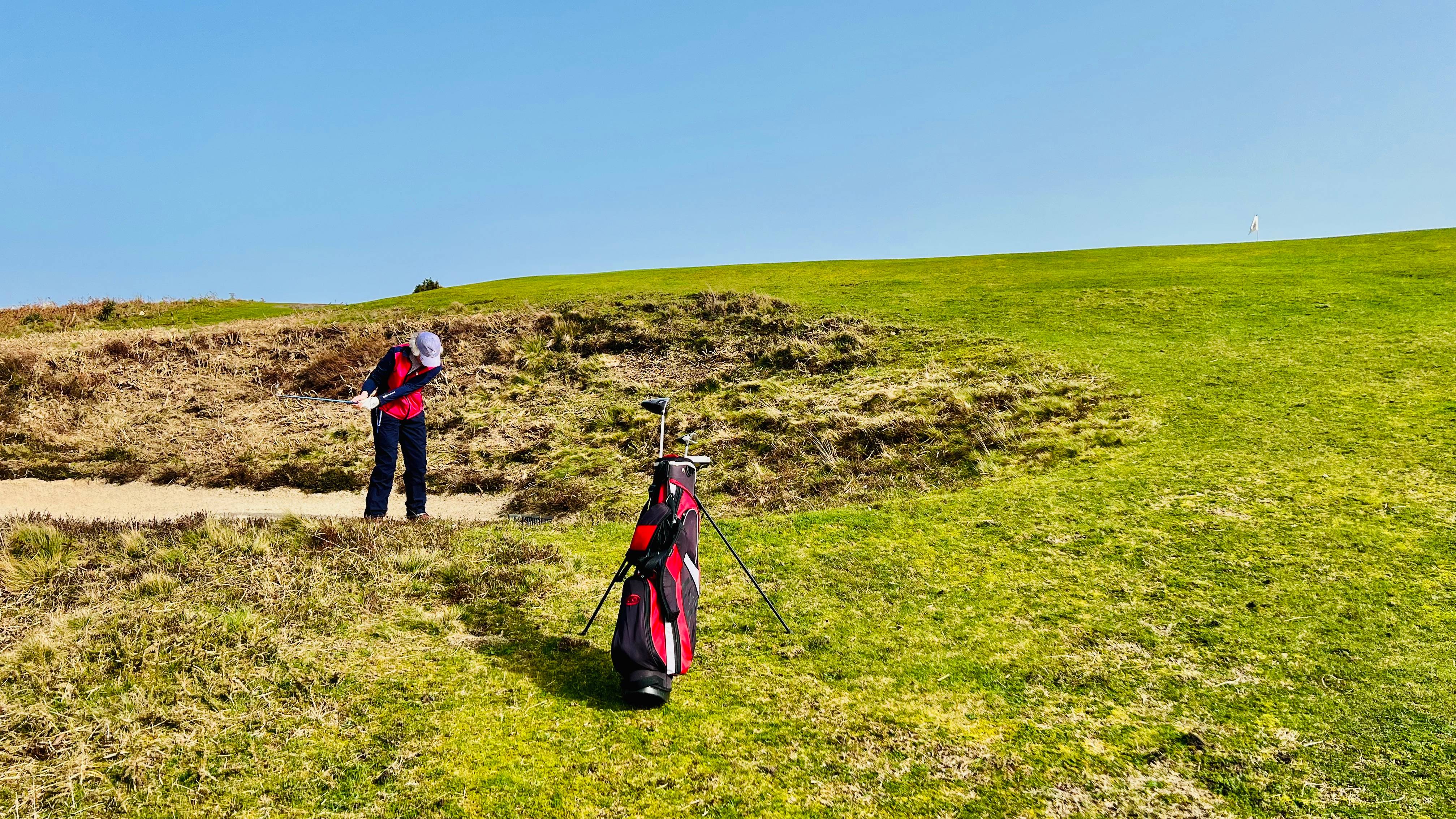 Female golfer playing out of a bunker