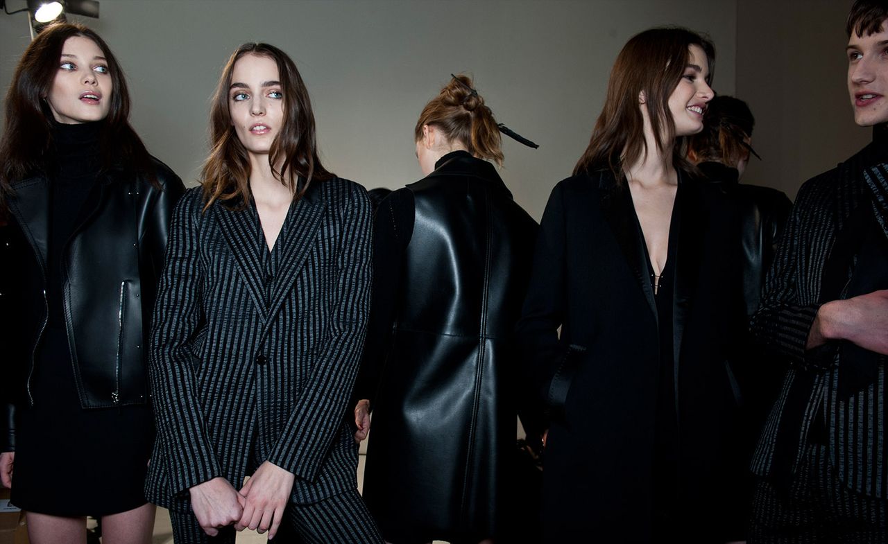 Models wearing black leather jackets with fur and gray and black striped suits, from the Costume National A/W 2015 collection.