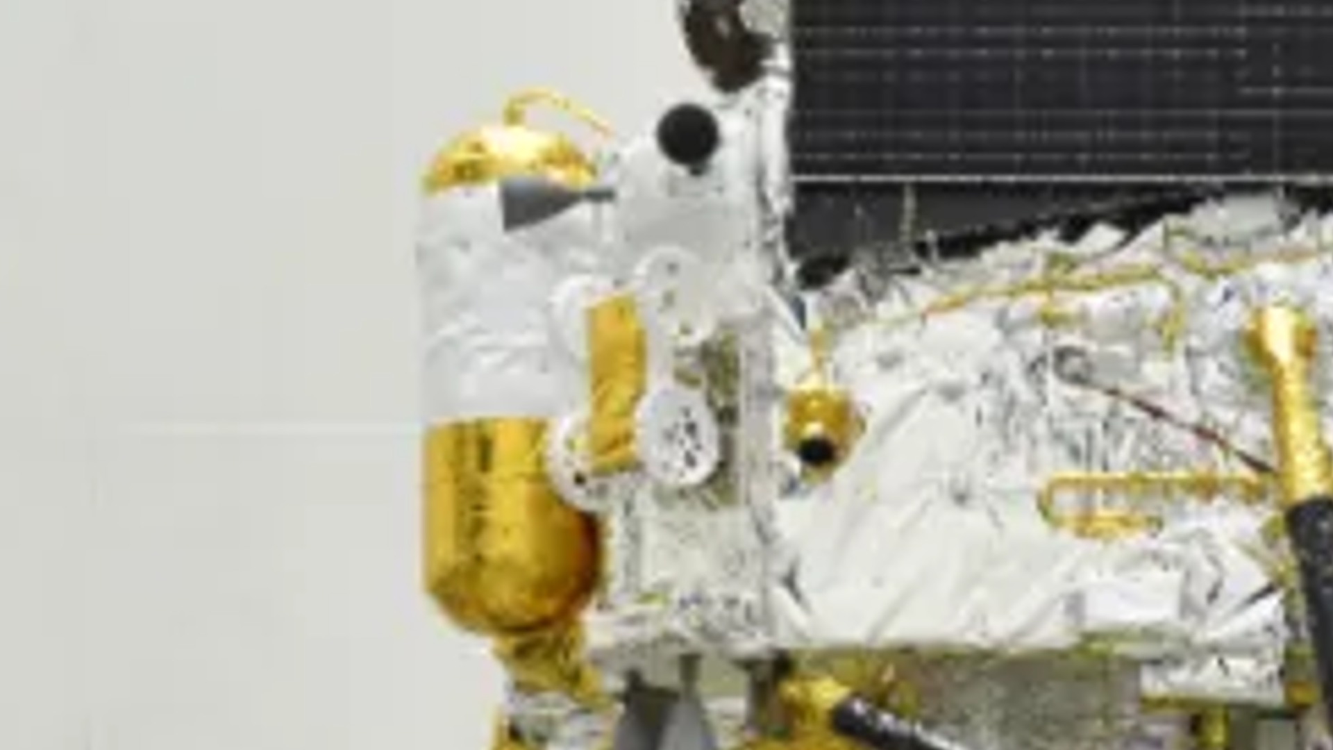 A close up of a tiny gold and white moon rover on the side of a Chinese spacecraft.