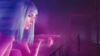 Still from the movie "Bladerunner 2049" Giant AI woman pointing directly at a man wearing a trench coat on a bridge.