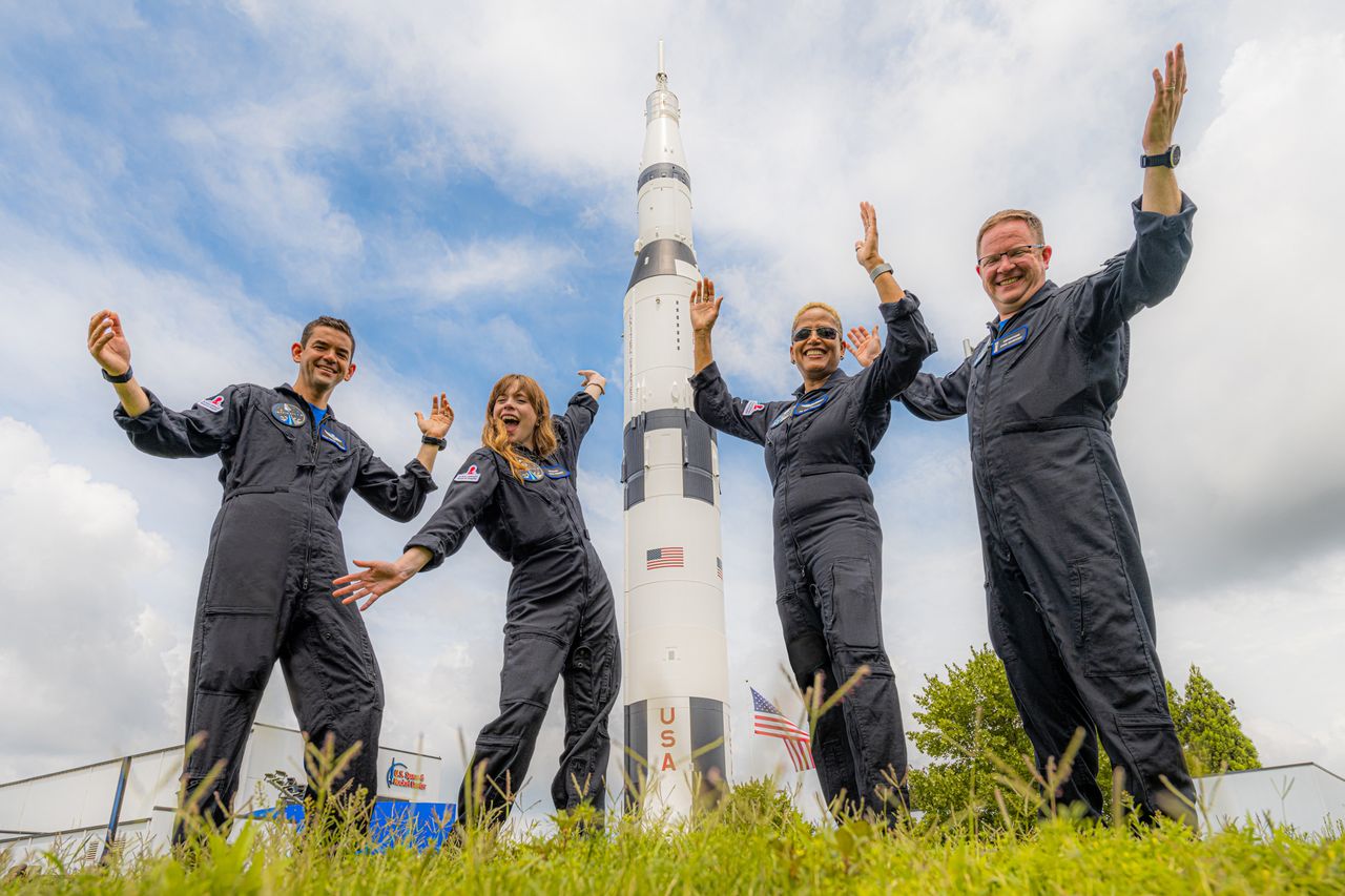 SpaceX's Inspiration4 crew pose with a Saturn V rocket at the U.S. Space and Rocket Center in Huntsville, Alabama.