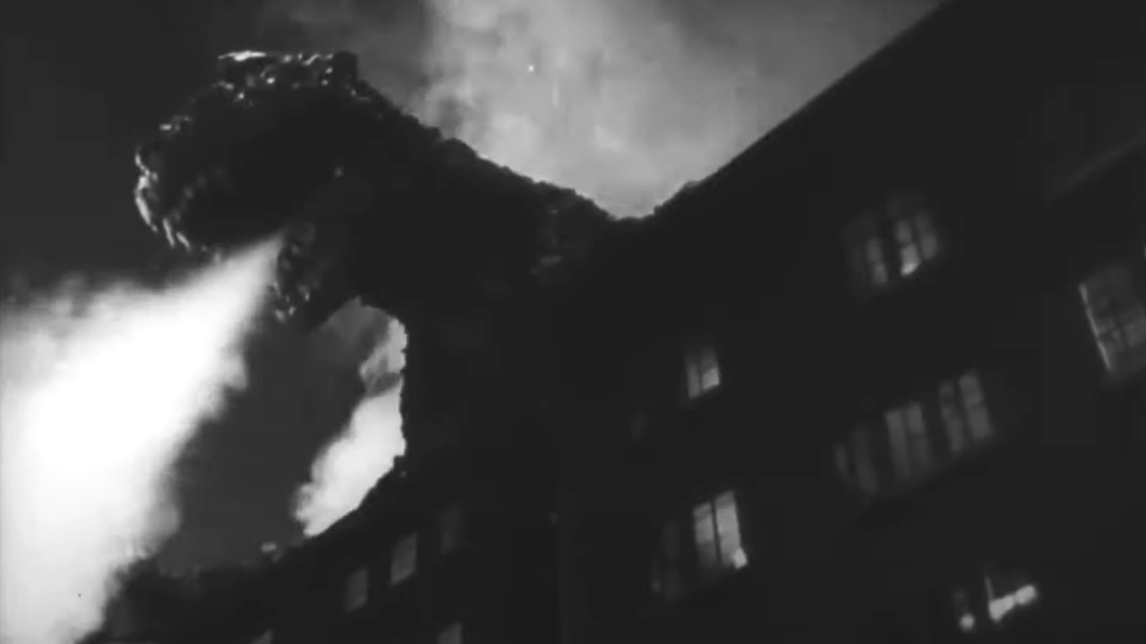 Godzilla uses his heat ray while looming over a building in Godzilla.