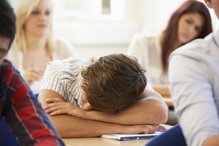 A teen falls asleep during class. 